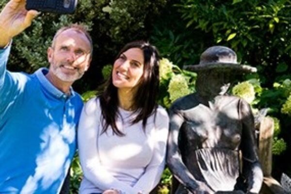 A couple sat next to a sculpture of a lady sat on a bench at Stillingfleet Lodge Gardens